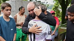 In Juiz de Fora trösten Freunde seinen Vater bei der Trauerfeier und Beisetzung eines elfjährigen Opfers von Starkregen und Überschwemmungen.