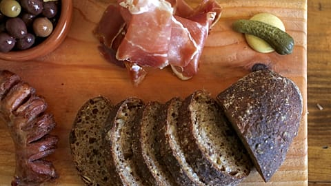 Тарелки с маринованными оливками, чесноком, свининой, колбасой и солеными огурцами на деревянном блюде в ресторане Petasca Tasca в Сономе, Калифорния, 10 мая 2016 года.