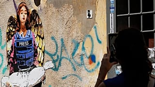 صورة تعبيرية_ امرأة تلتقط صورة للوحة "الملاك"، التي رسمها فنان الشارع هاري غريب في وقت سابق من هذا العام، والمخصصة للصحفيين الذين قُتلوا في غزة،