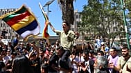 أشخاص يرددون هتافات وهم يلوّحون بالعلم الدرزي خلال تجمع أسبوعي في السويداء جنوبي سوريا، في 20 سبتمبر/أيلول 2025.