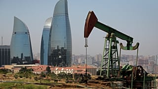FILE - In this 19 June 2015 file photo, skyscrapers stand in the background as an oil pump works a nearby hill in Baku, Azerbaijan.