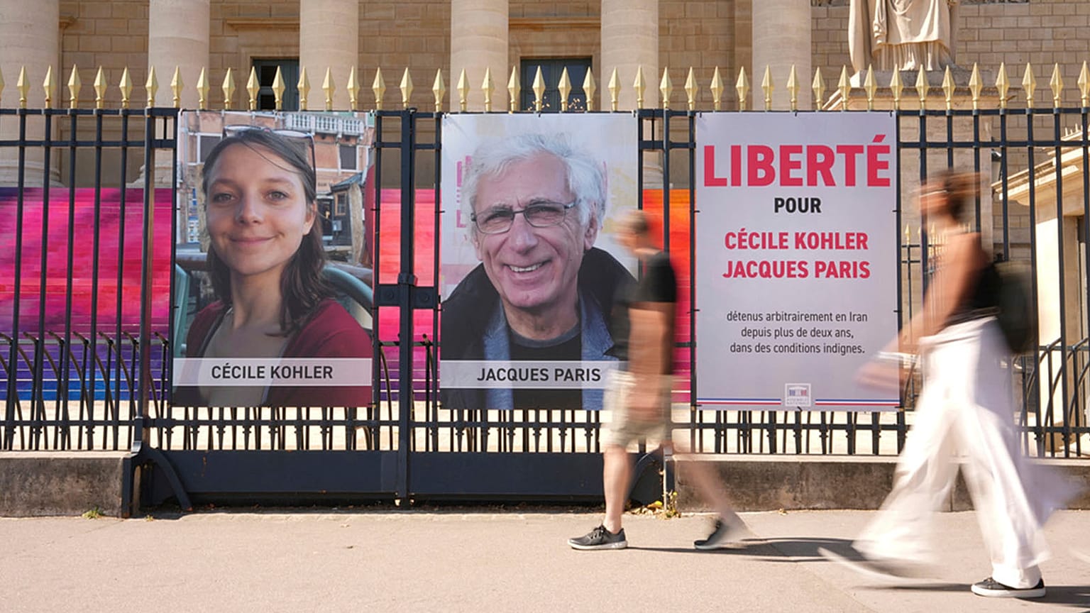 FILE - People walk past the portraits of French nationals Cecile Kohler and Jacques Paris in front of the French National Assembly in Paris, 3 July 2025