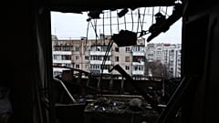 In Saporischschja: Durch das zerbrochene Fenster eines von einer russischen Drohne getroffenen Wohnblocks fällt der Blick auf ein Wohnviertel.