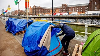 Shinwari, former Afghan army captain and asylum seeker, closes his tent in a makeshift camp outside the Petit Chateau reception center in Brussels, Tuesday, Jan. 31, 2023.