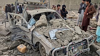 Afganistan'ın Nangarhar eyaletindeki İnsanlar, Pakistan ordusunun saldırılarında ağır hasar almış bir aracın yanında duruyor, 22 Şubat 2026