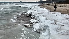 Eine Frau geht an einem kalten und windigen Mittwoch, 4. Februar 2026, an einem eisbedeckten Ostseestrand in Scharbeutz, Deutschland, spazieren (AP Photo/Michael Probst)