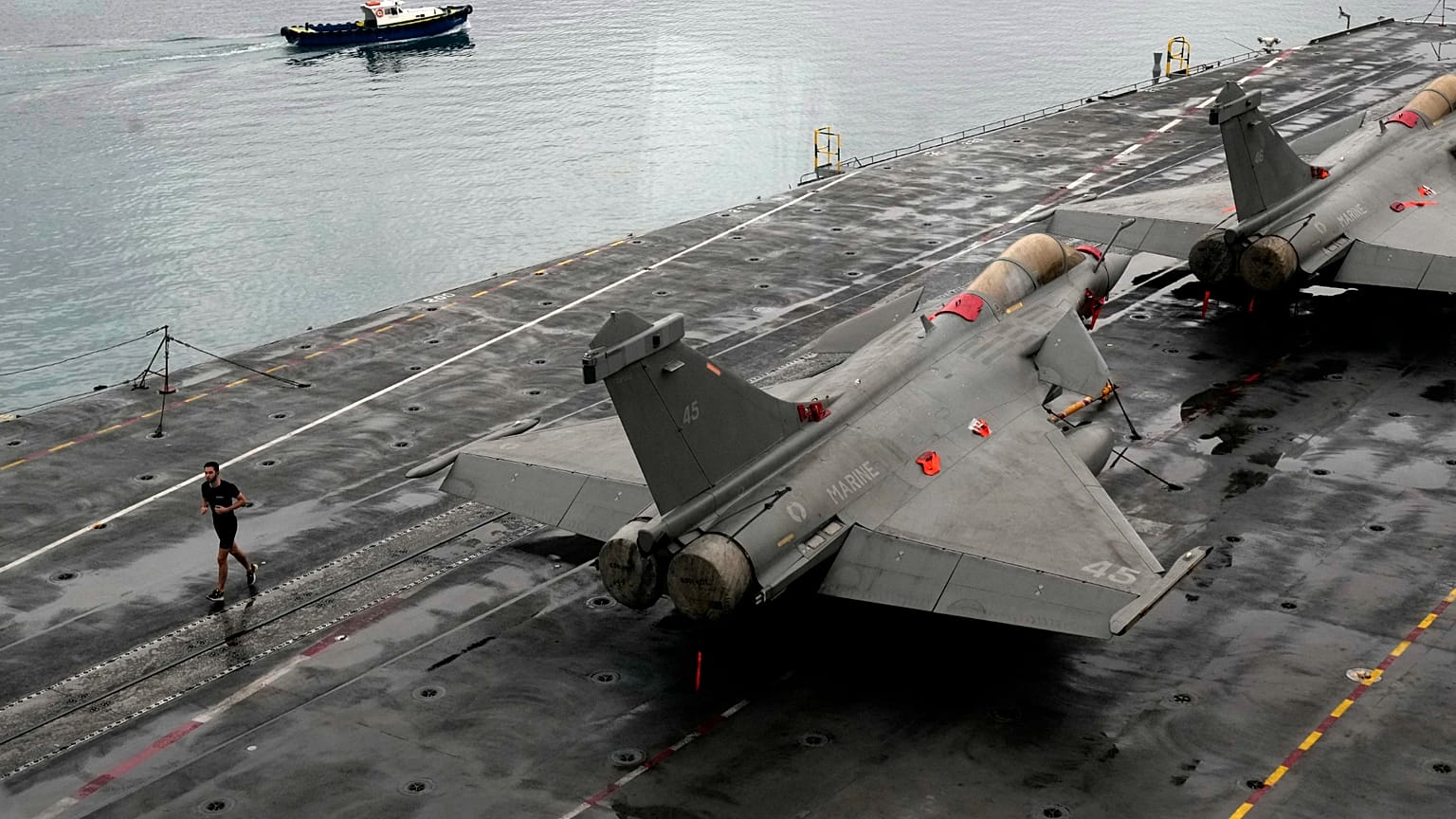 عضو في الطاقم الفرنسي يركض قرب مقاتلات رافال على متن حاملة الطائرات الفرنسية التي تعمل بالطاقة النووية شارل ديغول، في ميناء ليماسول بقبرص