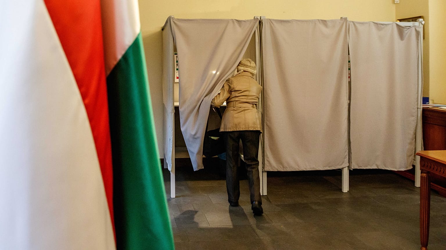 Egy nő belép a szavazófülkébe a magyarországi országgyűlési választáson és gyermekvédelmi népszavazáson Magyarország ungvári főkonzulátusán 2022. április 3-án.