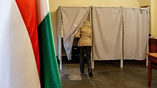 Egy nő belép a szavazófülkébe a magyarországi országgyűlési választáson és gyermekvédelmi népszavazáson Magyarország ungvári főkonzulátusán 2022. április 3-án.