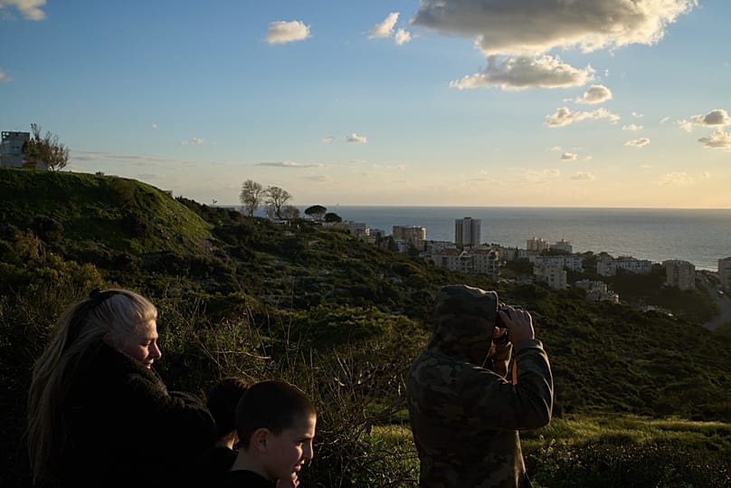 Man uses a binocular looking for the possible arrival of the USS Gerald R. Ford in the Mediterranean Sea near the coast of Haifa, northern Israel, Friday, Feb. 27, 2026