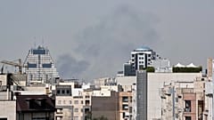 Des personnes regardent la fumée s'élever dans le ciel après une explosion à Téhéran, en Iran, le samedi 28 février 2026.