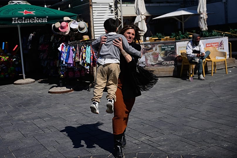 People rush to take shelter as warning sirens sound following missile fired towards Israel, in Tel Aviv,