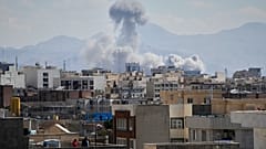 La gente osserva da un tetto mentre una colonna di fumo si alza dopo uno sciopero a Teheran, Iran, domenica 1 marzo 2026. (Foto AP/Vahid Salemi)
