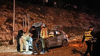 قوات الأمن الإسرائيلية تعاين موقع إصابة مباشرة على طريق، عقب غارة صاروخية إيرانية في القدس، الأحد.