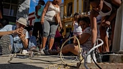 Μια ομάδα ανθρώπων συγκεντρώνονται στο δρόμο για να φορτίσουν τα κινητά τους τηλέφωνα.