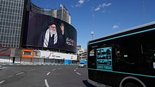 Veículos passam por um outdoor que mostra um retrato do falecido líder supremo iraniano, o aiatolá Ali Khamenei, que foi morto na campanha militar dos EUA e Israel.