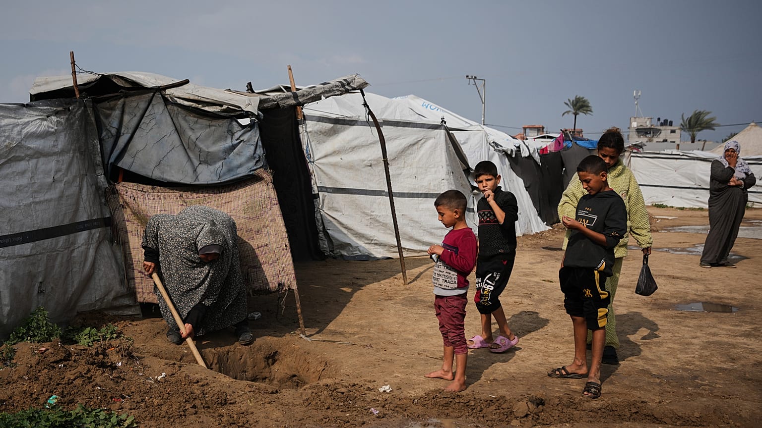 النازحة الفلسطينية لبنى أبو سرية تحفر قناة صغيرة لتصريف مياه الأمطار التي غمرت خيمتها في دير البلح، وسط قطاع غزة.