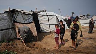 النازحة الفلسطينية لبنى أبو سرية تحفر قناة صغيرة لتصريف مياه الأمطار التي غمرت خيمتها في دير البلح، وسط قطاع غزة.