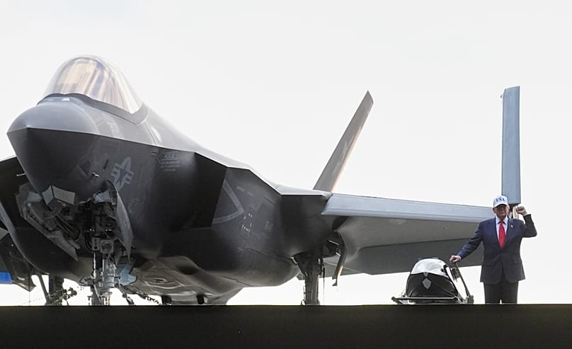 Il presidente Trump accanto a un jet da combattimento a bordo della portaerei Uss George Washington, alla base navale statunitense di Yokosuka, Tokyo, 28 ottobre 2025