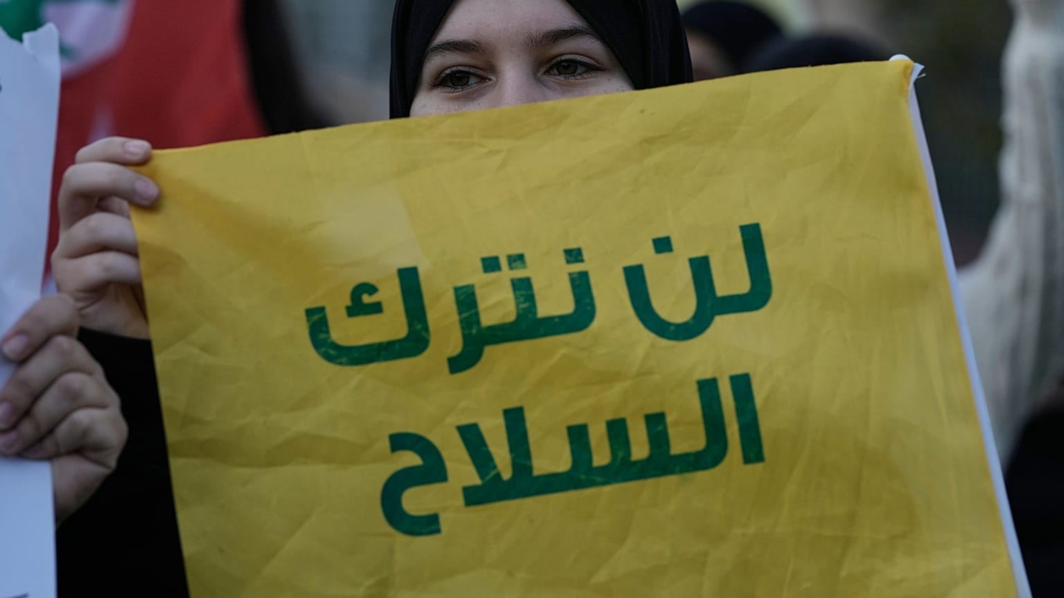 سيدة من أنصار حزب الله في بيروت ترفع لافتة تقول: "لن نترك السلاح" خلال مظاهرة تندد بالغارات الإسرائيلية على لبنان بتاريخ 4 فبراير/شباط 2026.