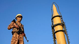 FILE: An Iranian armed forces member stands guard in front of a domestically-built missile displayed during the Basij paramilitary force parade in Tehran, 10 January 2025
