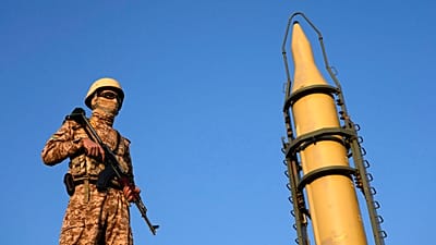 FILE: An Iranian armed forces member stands guard in front of a domestically-built missile displayed during the Basij paramilitary force parade in Tehran, 10 January 2025