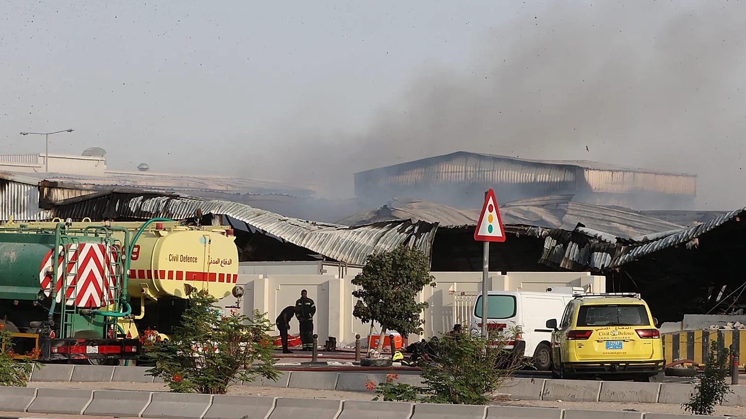 Firefighters work as smoke rises outside a damaged warehouse in an industrial area in Al Rayyan, Qatar, following an Iranian strike, March 1, 2026. 