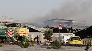 Firefighters work as smoke rises outside a damaged warehouse in an industrial area in Al Rayyan, Qatar, following an Iranian strike, March 1, 2026. 