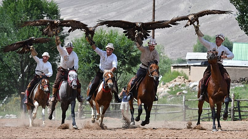 Kirgisische Jäger reiten mit ihren Steinadlern beim traditionellen Salbuurun-Festival der Adlerjagd