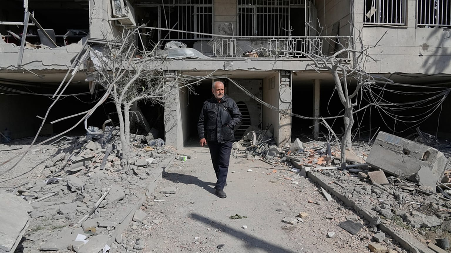 Un homme marche dans la cour de son immeuble de bureaux, endommagé lors d'une frappe contre des installations policières pendant la campagne militaire américano-israélienne.