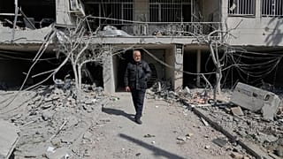 Un homme marche dans la cour de son immeuble de bureaux, endommagé lors d'une frappe contre des installations policières pendant la campagne militaire américano-israélienne.