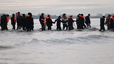 يسير مهاجرون في المياه لصعود قارب صغير في محاولة للوصول إلى بريطانيا