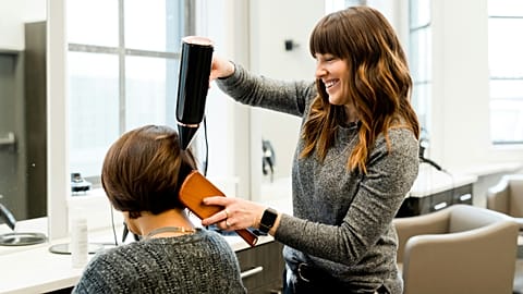 A hairdresser blow-drying a client's hair.