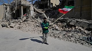 صبي يلوح بالعلم الإيراني أمام مركز للشرطة تعرض للهجوم خلال الحملة العسكرية الأمريكية الإسرائيلية في طهران، إيران، الأربعاء 4 مارس 2026.