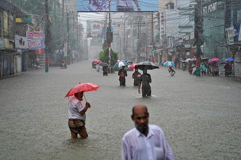 People navigate a flooded street following incessant rains in Feni, a coastal district in southeast Bangladesh bordering with Indian Tripura state, Bangladesh, Aug. 22, 2024