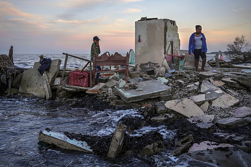FILE - Yahir Mayoral and Emily Camacho walk amid the rubble of their grandmother's home, destroyed by flooding, El Bosque, Mexico, Nov. 30, 2023