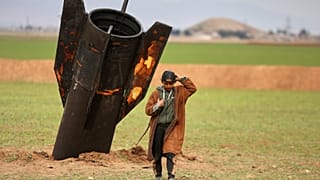 يسير راعٍ مبتعدًا عن مقذوف إيراني غير منفجر سقط في حقل مفتوح في ضواحي مدينة القامشلي شرقي سوريا، الأربعاء 4 مارس/آذار 2026.