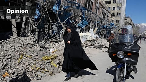 A woman walks past a building which was damaged after a strike on a police station amid the U.S.–Israeli military campaign in Tehran, Iran, Tuesday, March 3, 2026.