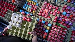 Eine Käuferin wählt am orthodoxen Karfreitag, dem 18. April 2025, auf einem Grünmarkt in Belgrad, Serbien, handverzierte Ostereier aus.