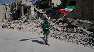 A boy waves an Iranian flag in front a police facility struck during the U.S.–Israeli military campaign in Tehran