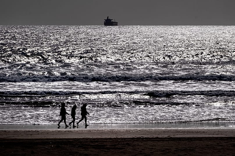 ARQUIVO. Três mulheres caminham na praia em Sines, Portugal, abr. 2024