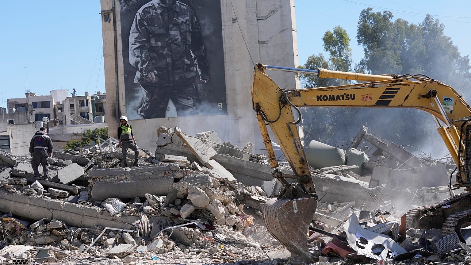 صق عملاق يظهر القائد العسكري الراحل لحزب الله عماد مغنية، بينما يتفقد العمال مبنى مدمرا ضربته غارة جوية إسرائيلية في بلدة النبطية جنوب لبنان، الخميس 5 مارس 2026. 