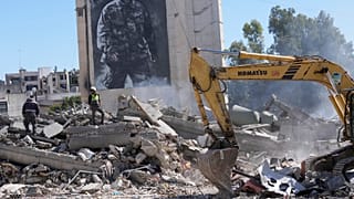 صق عملاق يظهر القائد العسكري الراحل لحزب الله عماد مغنية، بينما يتفقد العمال مبنى مدمرا ضربته غارة جوية إسرائيلية في بلدة النبطية جنوب لبنان، الخميس 5 مارس 2026. 