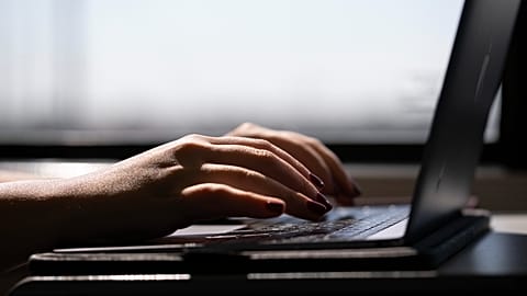 a woman typing on a laptop on a train in New Jersey. 