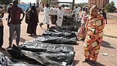 يتفقد أقارب الضحايا أكياس جثث ضحايا النزاع المستمر منذ عامين في السودان، بعد أن نقلت هيئة الهلال الأحمر السوداني الرفات من قبور مؤقتة إلى مقبرة محلية في الخرطوم
