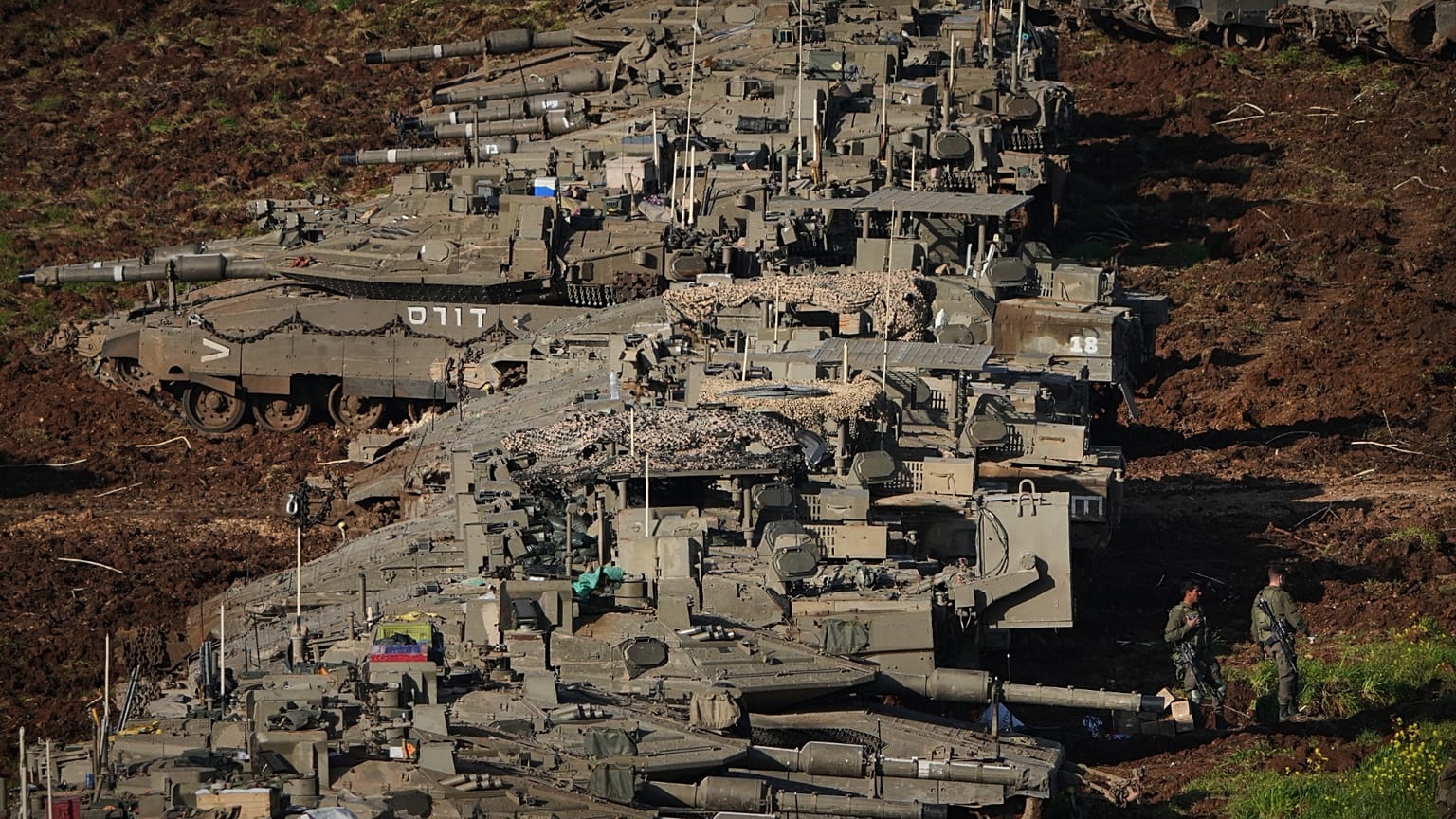 Israeli soldiers work on tanks at a staging area in northern Israel.