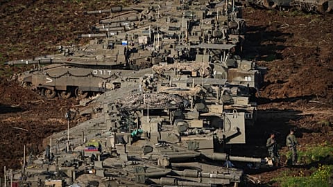 Israeli soldiers work on tanks at a staging area in northern Israel.