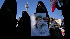 امرأة تحمل صورة المرشد الأعلى الإيراني الراحل علي خامنئي، بينما يسير أنصار الحكومة في مسيرة احتجاجًا على الحملة العسكرية الأمريكية-الإسرائيلية الجارية،