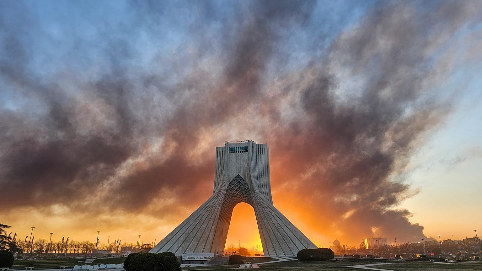 يتصاعد الدخان خلف نصب آزادي (الحرية) في طهران، إيران، في 3 مارس/آذار 2026، عقب الهجوم الأمريكي-الإسرائيلي.