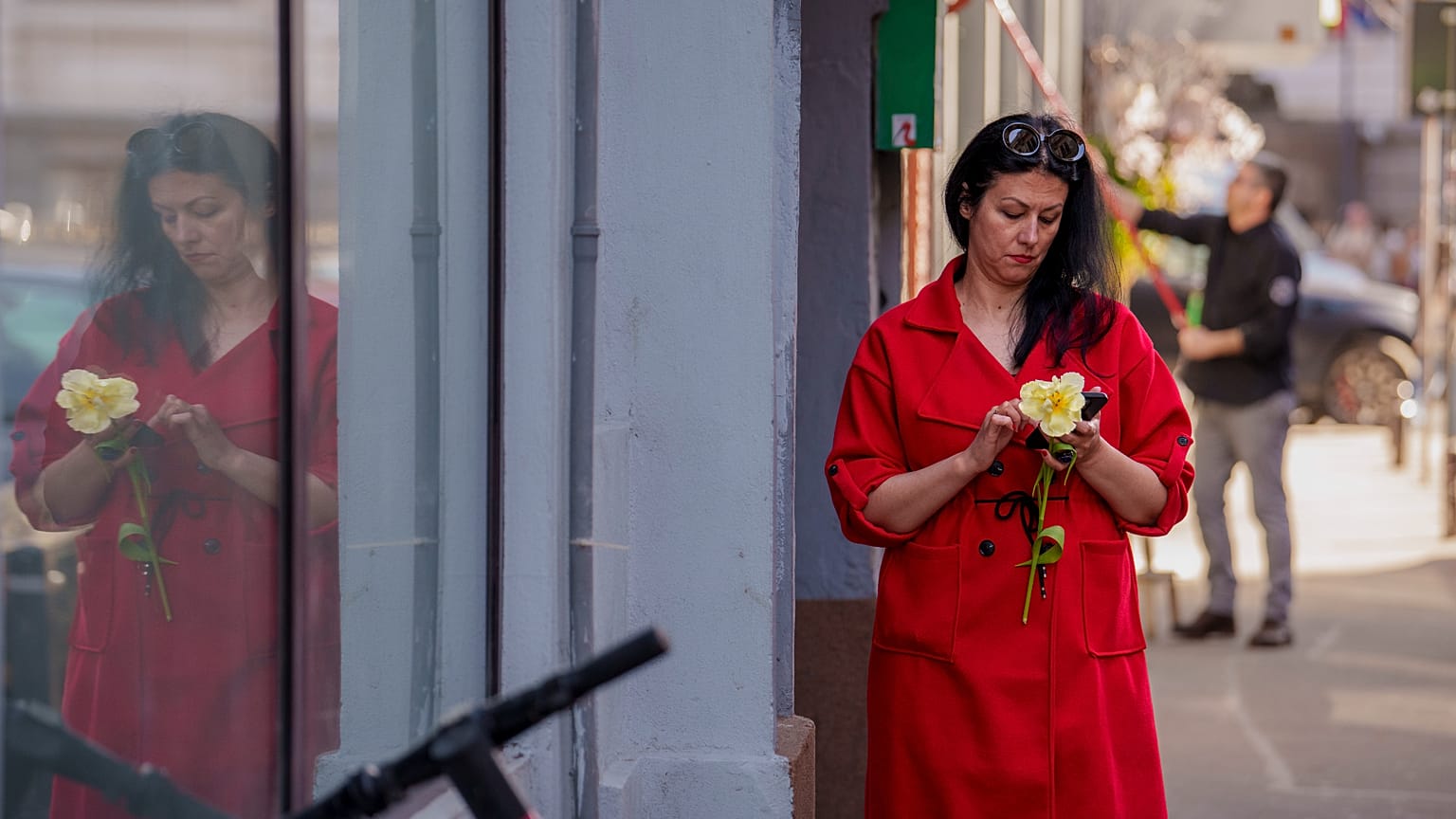 ARQUIVO (08.03.2025): Uma mulher segura uma flor enquanto olha para um telemóvel no Dia Internacional da Mulher, no centro de Bucareste.